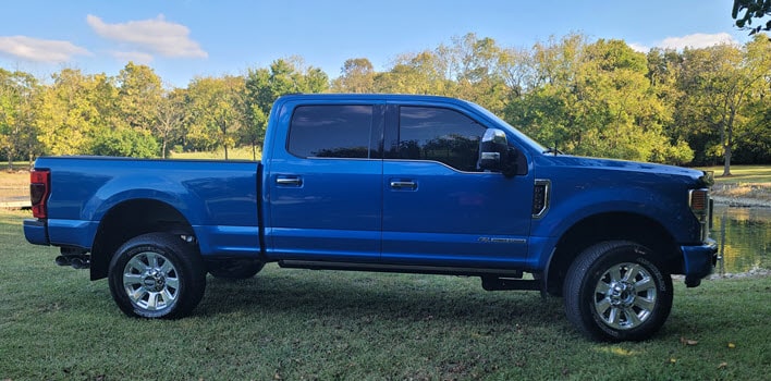 The Value of Professional Vehicle Detailing Services. | Blue 2020 Ford Platinum F-250 Super Duty Detailed and Sitting Pretty in a Field on the Side of a Pond.